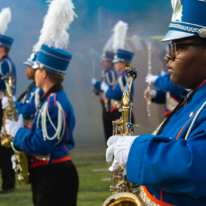  AD Marching Band in full uniform on the field at a football halftime performance.